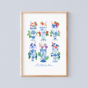 Puede incluir: Una impresión enmarcada con seis ilustraciones de batidos decorativos. Cada batido está en un vaso con estampado floral azul y blanco, cubierto con varias frutas y adornos. La palabra "Milkshakes" está escrita en cursiva en la parte inferior.