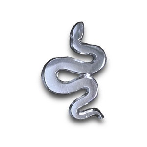 May include: A silver-colored snake-shaped decorative item. The snake is coiled in a stylized, serpentine form, with a smooth, reflective surface. The design is set against a white background, creating a contrast that highlights the snake's form.