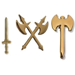 May include: Three gold-colored metal pins depicting fantasy weapons: a sword, a pair of crossed axes, and a single axe.
