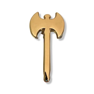 May include: A gold-colored metal axe pin with a double-headed blade and a long handle.