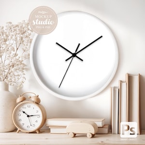 May include: A white wall clock with black hands, set against a neutral background. The clock is surrounded by decorative elements, including a wooden alarm clock, books, and a small wooden car. The image includes the text "MOCKUP studio PNG & PSD".