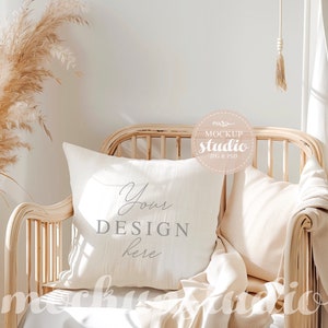 以下が含まれることがあります： 白い枕に「Your Design Here」という文字が書かれており、薄い茶色の籐製の椅子に白い毛布とクリーム色の枕が置かれています。