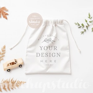 Könnte beinhalten: Weißer Kordelzugbeutel-Mockup mit einem Zweig mit Blättern und dem Text "Your Design Here" auf weißem Hintergrund.