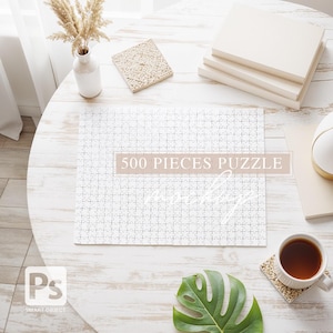 Könnte beinhalten: Ein weißes 500-teiliges Puzzle, teilweise zusammengesetzt, auf einem hellen Holztisch. Der Text "500 PIECES PUZZLE" ist auf dem Puzzle zu sehen. Eine Tasse Tee, Bücher und dekorative Gegenstände umgeben das Puzzle.