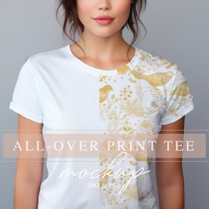 May include: A white t-shirt with a gold floral and bird print. The print covers the entire shirt. The text "ALL-OVER PRINT TEE" is on the bottom of the shirt.