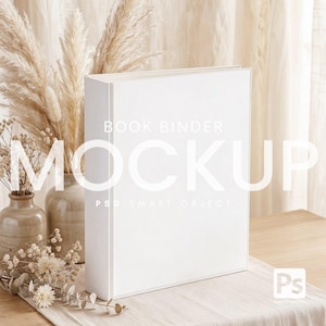 May include: A white book binder mockup stands upright on a light-colored surface, with the text "BOOK BINDER MOCKUP" overlaid on the front. Dried flowers and vases are arranged in the background, creating a neutral and aesthetic composition. The image is well-lit, highlighting the binder's clean lines.