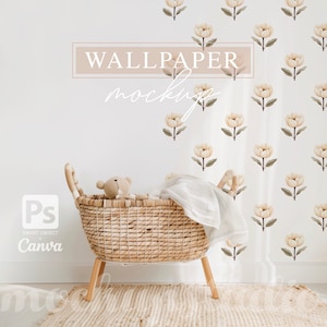 Op de afbeelding: Een witte muur met een behangmockup met een herhalend patroon van beige bloemen. Een rieten mand met een teddybeer erin staat voor de muur.