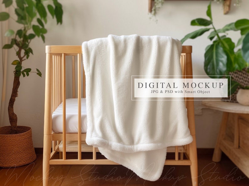 May include: White plush blanket draped over a wooden crib with a white sheet. The crib is in a room with a plant and a wooden side table. The text "DIGITAL MOCKUP JPG & PSD with Smart Object" is on a white rectangle.