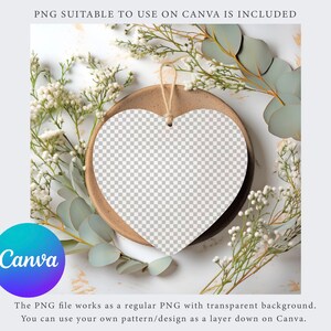 May include: A white heart-shaped sign with a transparent background, hanging from a string, on a brown plate with white flowers and green leaves around it.