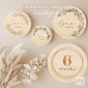May include: Four wooden baby milestone signs with floral designs. The signs read "Four Months", "Ten Months", "One Month", and "6 Months".