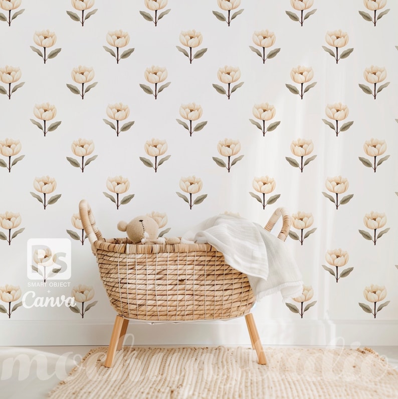 May include: A white wall with a repeating pattern of beige flowers. A wicker basket with a white blanket and a teddy bear sits in front of the wall.