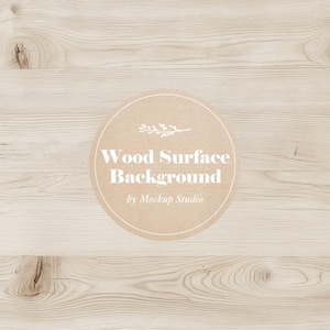 May include: A light brown wood surface background with a circle in the center. The circle is brown with a white outline and contains a small white floral design and the text "Wood Surface Background by Mockup Studio".