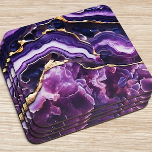Può includere: Set di quattro sottobicchieri in agata viola e oro. I sottobicchieri presentano un motivo a spirale di viola e oro, che ricorda una pietra naturale.
