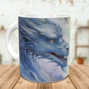 May include: A white ceramic mug featuring a blue dragon design. The dragon's head is facing the right side of the mug and its eyes are open. The dragon is surrounded by a white background with a light blue haze.