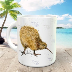 May include: White ceramic mug featuring a brown and white illustration of a kiwi bird on a white background with blue watercolour splatter.