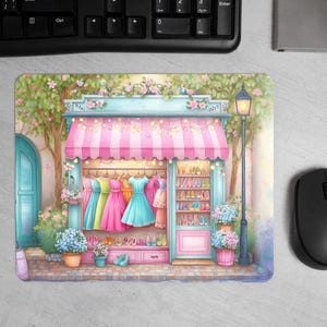 May include: A watercolour illustration of a boutique with a pink and white striped awning, showcasing colourful dresses and shoes. The shop is decorated with flowers and a vintage street lamp. The image is on a mousepad.