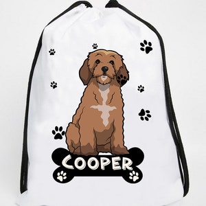 Può includere: Borsa a cordoncino bianca con un'illustrazione di un cartone animato di un cane marrone e bianco seduto su un osso nero con il nome "COOPER" scritto su di esso. La borsa è decorata con impronte di zampe nere.