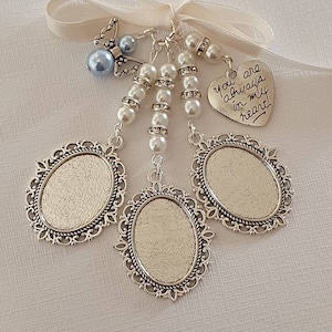 May include: A decorative charm featuring three silver-toned oval photo frames with ornate edges, suspended from a white ribbon. The piece includes white pearl beads, silver spacers, a small blue bead, a butterfly charm, and a heart-shaped tag with the text "you always in my heart".