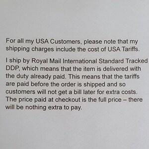 May include: A white document featuring black printed text that explains shipping policies for USA customers, specifically detailing that tariffs are included in the shipping charges and that all duties are paid prior to the order being shipped.
