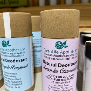 Op de afbeelding: Een bruine kartonnen buis met een wit etiket waarop "GreenLife Apothecary" en "Natuurlijke Deodorant Lavendel Kamille" staat. Het etiket vermeldt ook "Goed voor jou en goed voor de planeet" en somt de ingredi&euml;nten op: "Aluminiumvrij, parabenenvrij, propylenglycolvrij, milieuvriendelijke verpakking, natuurlijk antibacterieel, verzachtend en fris".