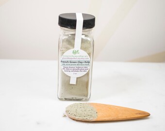 May include: A glass jar filled with green French green clay and kelp powder. The jar has a white label with the text "GreenLife Apothecary greenlifeupothecary.etsy.com French Green Clay+Kelp oily acne prone skin face mask Deep cleanse, balances skin PIL Aids in detoxification and toning, exfoliates the skin 2 oz". A wooden spoon with a scoop of the green clay powder is next to the jar.
