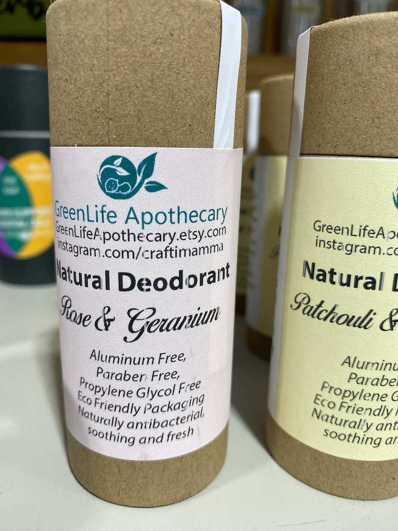 Op de afbeelding: Twee kartonnen buizen met witte etiketten. Het etiket op de linker buis luidt "GreenLife Apothecary GreenLifeApothecary.etsy.com Instagram.com/craftimamma Natuurlijke deodorant Rozen & Geranium Aluminiumvrij, Paraben vrij, Propylenglycol vrij Ecologisch verpakte Natuurlijk antibacterieel, verzachtend en fris". Het etiket op de rechter buis luidt "GreenLifeAp instagram.co Natuurlijke deodorant Patchouli & Aluminium Paraben Propylenglycol G Ecologisch verpakte Natuurlijk ant verzachtend ar".