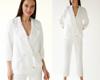 May include: A white double-breasted blazer with gold buttons and a matching pair of pants. The blazer has a relaxed fit and a slightly cropped length.