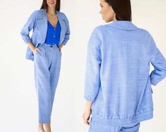 May include: A light blue linen blazer and matching pants. The blazer has a relaxed fit and a slightly cropped length. The pants have a straight leg and a mid-rise waist.