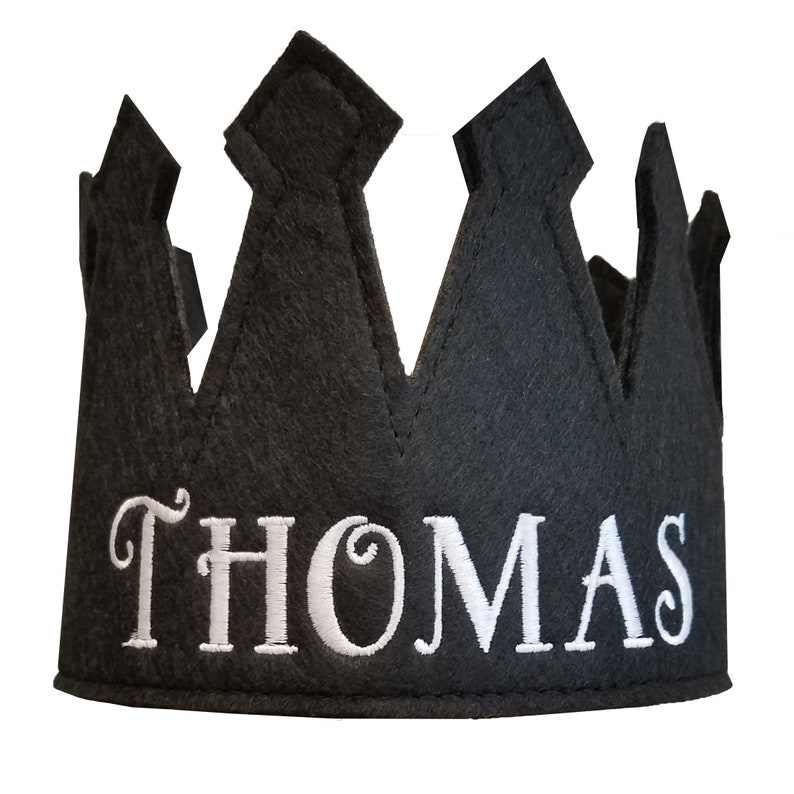May include: Black felt crown with white embroidered text "THOMAS" on the front.