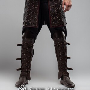 May include: A person wearing a full suit of brown leather armor with a crossbow strapped to their shoulder. The armor is decorated with rivets and has a medieval aesthetic.