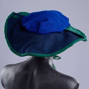 K&ouml;nnte beinhalten: Ein breitkrempiger Hut mit blauer Oberseite und gr&uuml;nem Rand. Der Hut ist aus Filz und hat ein schlichtes Design.