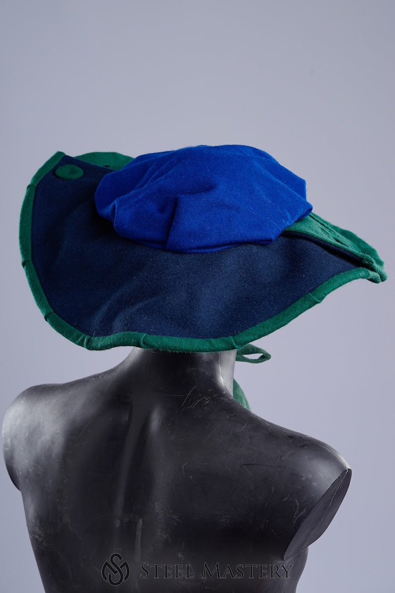 K&ouml;nnte beinhalten: Ein breitkrempiger Hut mit blauer Oberseite und gr&uuml;nem Rand. Der Hut ist aus Filz und hat ein schlichtes Design.