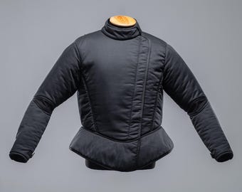 Puede incluir: Chaqueta acolchada negra con cuello alto y cierre de cremallera diagonal. La chaqueta tiene una silueta ajustada y un dobladillo ligeramente acampanado.