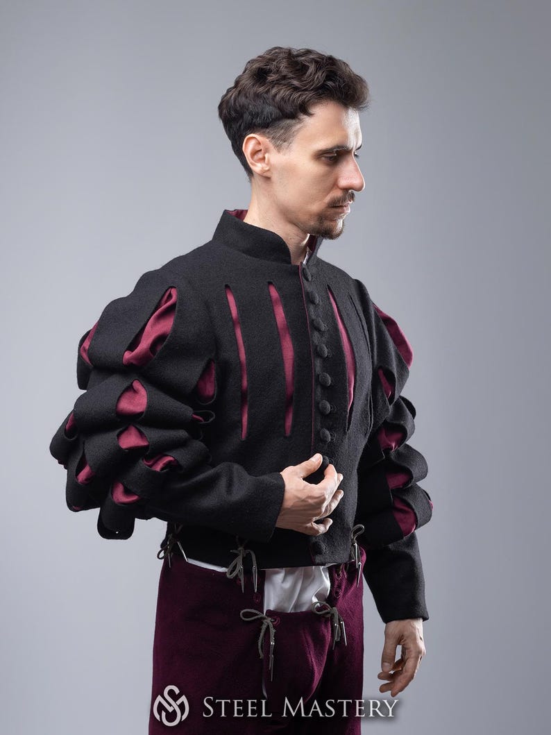 May include: A black doublet with burgundy accents and puffed sleeves. The doublet has a high collar and is fastened with buttons. The sleeves have a unique design with cutouts and layered fabric.