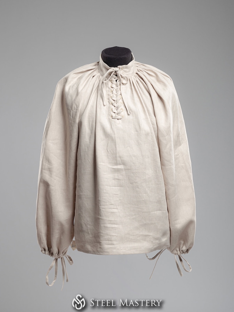 May include: A beige linen shirt with a lace-up neckline and long sleeves. The sleeves have ties at the cuffs.