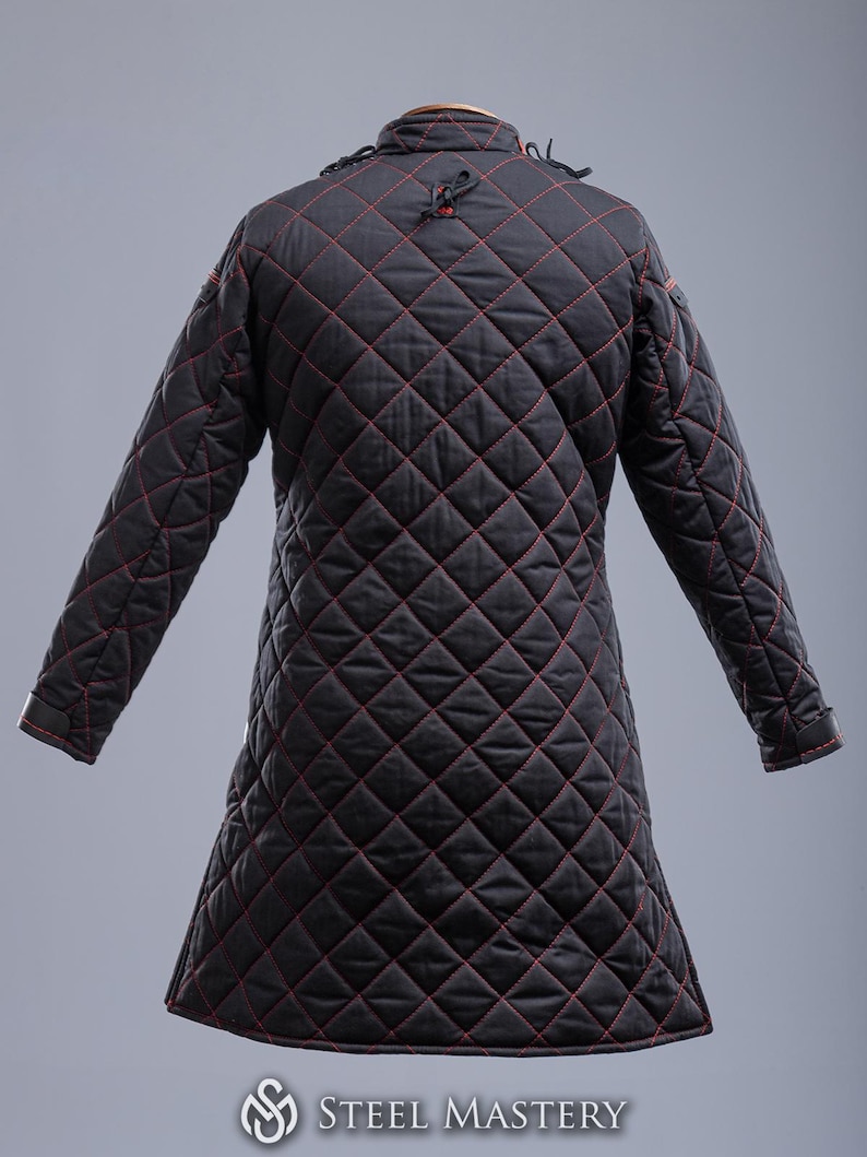 May include: Black quilted jacket with red stitching. The jacket has a high collar and long sleeves. The jacket is made of a thick, durable fabric and is designed for warmth and protection.