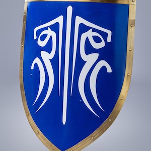 Puede incluir: Un escudo azul con un diseño estilizado blanco. El escudo tiene un borde y remaches de latón.