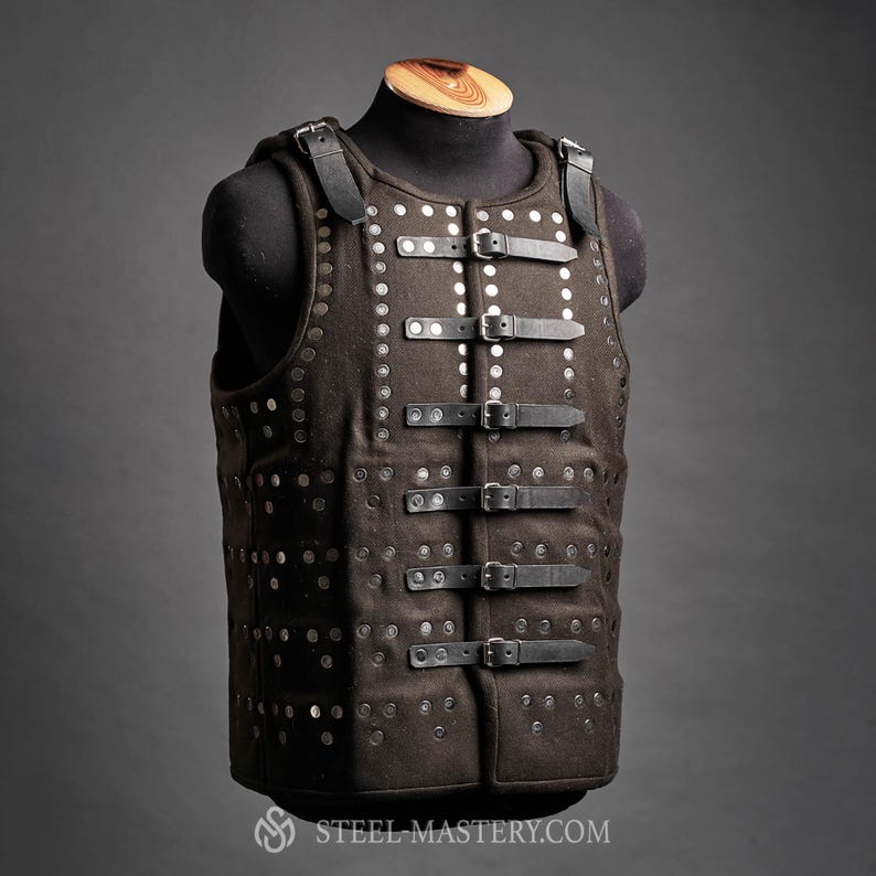Pode incluir: Um colete castanho de estilo medieval com rebites prateados e correias e fivelas de couro preto. O colete &eacute; exibido em um manequim preto. O colete tem al&ccedil;as e um decote alto. O logotipo Steel Mastery &eacute; vis&iacute;vel na parte inferior.