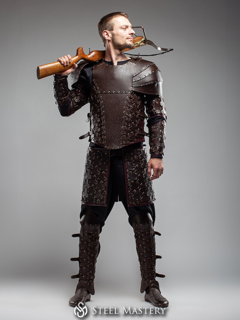 May include: A person wearing a full suit of brown leather armor with a crossbow strapped to their shoulder. The armor is decorated with rivets and has a medieval aesthetic.