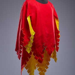 May include: A red tunic with yellow detailing and a flame-like pattern along the hem. The sleeves are lined with yellow. The garment is displayed on a black mannequin head.