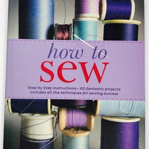 May include: A book cover titled "how to SEW" with stacked spools of colourful thread. The cover features a purple banner with the title and a needle and thread illustration. The book promises step-by-step instructions and 20 projects.