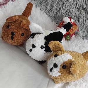 May include: Three crocheted plush dog toys. One is brown, one is black and white, and one is brown and white.