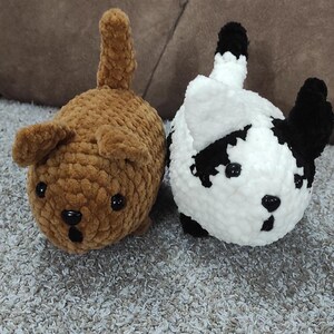 May include: Two crocheted stuffed animals shaped like dogs. One is brown with a long tail and the other is white with black markings.