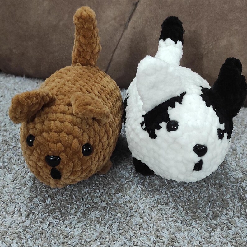 May include: Two crocheted stuffed animals shaped like dogs. One is brown with a long tail and the other is white with black markings.