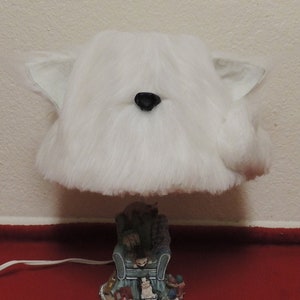 May include: White furry lampshade with a black nose and a white ceramic base with a scene of a dog sitting in a chair.
