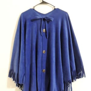 May include: A blue fleece poncho with a fringe trim and button closure. The poncho has a tie at the neck.