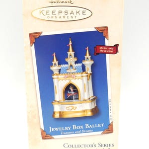 May include: A Hallmark Keepsake Ornament box featuring a jewelry box ballet design. The box has a blue background with a white and gold castle design. The text "Jewelry Box Ballet Treasures and Dreams" is visible.