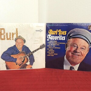 May include: Two vinyl record albums featuring Burl Ives. The left cover shows Burl Ives playing an acoustic guitar. The right cover, titled Burl Ives Favorites, features a portrait of Burl Ives wearing a cap, with a tracklist printed in white text.