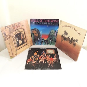 May include: Four vintage vinyl record albums. Album covers include "Bread - Manna", "Will O' The Wisp - Leon Russell", "Blood, Sweat & Tears", and "The Band - Stage Fright". The album covers feature various illustrations and text.