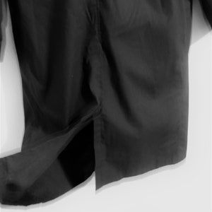 May include: A black long-sleeved shirt with a single slit in the back.